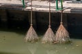 Old broomstick hanging by the canal for collecting garbage on the road Royalty Free Stock Photo
