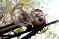 The old brown iron crusher wheel with black belt on the sky blue and green background