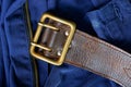 Old brown leather belt with brass buckle on blue pants Royalty Free Stock Photo