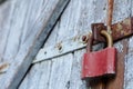 Old brown padlock on a gray door with wooden planks of cracked paint and rust. Vintage gates with metal stripes and bolts Royalty Free Stock Photo