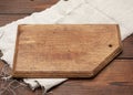 Old brown rectangular wooden kitchen cutting board and gray linen napkin on the table Royalty Free Stock Photo