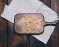Old brown rectangular wooden kitchen cutting board and gray linen napkin on the table Royalty Free Stock Photo