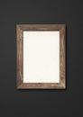 Old brown rustic wooden picture frame hanging on a black wall Royalty Free Stock Photo