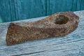 Old brown rusty battle ax on a gray board at the green wall Royalty Free Stock Photo