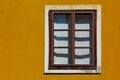 old brown wood window in vertical orientation in yellow color stucco exterior wall Royalty Free Stock Photo