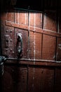 Old brown wooden door locked with a padlock and illuminated by a lamp. Spooky door in the dark Royalty Free Stock Photo