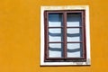 old brown wooden window in vertical orientation in yellow color stucco exterior wall Royalty Free Stock Photo