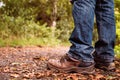 Old brown worn out hiking boots and blue jeans in a park. Selective focus. Outdoor adventure concept. Rugged lasting design
