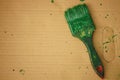 Old brush stained with green paint on brown paper sheet Royalty Free Stock Photo