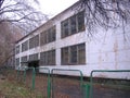 The old building of an abandoned school behind a fallen fence emptied in the fall idle Royalty Free Stock Photo