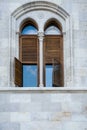 The old building from gray concrete blocks with narrow and beautiful windows with wooden sun blind. Royalty Free Stock Photo