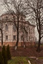 An old building in a park behind trees . Royalty Free Stock Photo