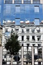 Old building and tree mirroring in a modern glass facade Royalty Free Stock Photo