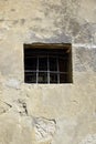 Old building wall with one small vintage window shuttered by iron rusty metal grid bar. Facade part detail in aged european city.