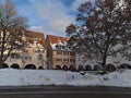 Old buildings with arcades and shops in center of Freudenstadt, Black Forest with snow-covered marketplace, bare trees and street.