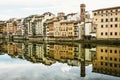 Old buildings with bell tower mirrored in the river Arno, Florence, Italy