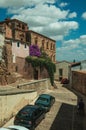 Old buildings and flowering trees over an alleyway with cars at Caceres