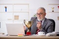 Old male employee being awarded with golden cup Royalty Free Stock Photo