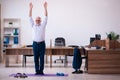 Old businessman employee doing sport exercises in the office Royalty Free Stock Photo