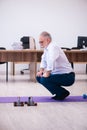 Old businessman employee doing sport exercises in the office Royalty Free Stock Photo