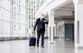 Old businessman in mask with travel bag at airport