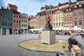 Old Busker sit down in front of The mermaid(Syren) Fountain,old town market place square in old town of Warsaw, Poland.