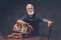 Old butcher cutting huge meat piece on wooden table