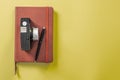 Camera on a closed red notebook with a pen on a yellow background Royalty Free Stock Photo