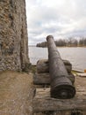 Old cannon that defended medieval fortification on the shore of river. Old ruined castle and its weapons.
