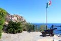 Old cannon, Italian flag and Cinque Terre village Manarola with colorful houses and Mediterranean Sea Royalty Free Stock Photo