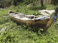Old canoe stranded on green grass beside the river