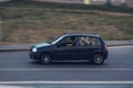 Old car Renault Clio 2 in motion. Young driver is distracted by his phone while driving a car