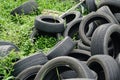 An old car tires stacked on the grass in a pile in area a car workshop, disposal recycling concepts