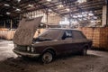 Old car uncovered with dust and dirt stuck in an abandoned building. Royalty Free Stock Photo