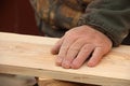 The old carpenter checks the quality of the sanding of the wood. A man`s hand strokes a wooden board. Making wooden furniture con