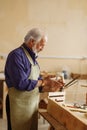 Old carpenter is rubbing his hands together after finishing work