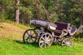 An carriage made of wood with large wheels without a horse on a mountainside on green grass. Retro and vintage from the story Royalty Free Stock Photo