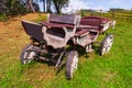 An carriage made of wood with large wheels without a horse on a mountainside on green grass. Retro and vintage from the story