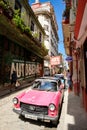 Old cars and decaying buildings on a narrow street in Old Havana