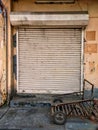An old cart in front of closed rusted shutter