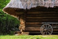 Old cart with wooden wheels against the background of a log house under thatched roof Royalty Free Stock Photo