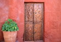 Old carved wood door on the orange red color rough wall with a big terracotta planters in Santa Catalina Monastery Royalty Free Stock Photo