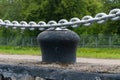 An anchor chain over a cast iron bollard on an old pier.