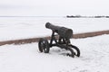 Old cast iron cannon on a winter snow-covered embankment