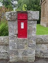 An Old cast Iron Traditional red Post Box set into the Stone Buttress of a Garden wall in the Village of Ford