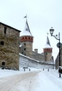 An old castle in the snow, a fortress made of stone, a tower with weathercocks, a fortress wall, a street lamp