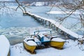 Old catamaran in the winter on the snow coast of the frozen river next to the long bridge.