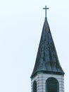 Old Catholic Church Steeple with Green Patina over Copper and Plain Cross at the Top Royalty Free Stock Photo