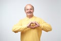 Old caucasian man in yellow tshirt making out of hands heart. Royalty Free Stock Photo