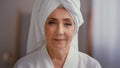 Old Caucasian middle-aged woman mature lady elderly model female with towel on head in bathrobe looking at camera Royalty Free Stock Photo